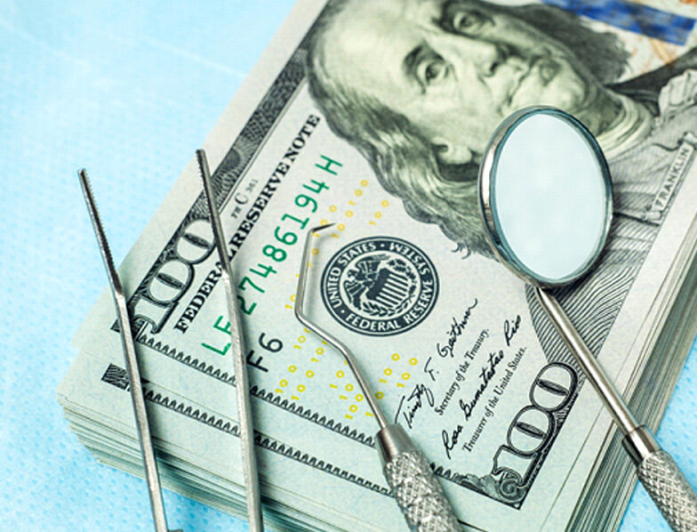 dental instruments on stack of cash