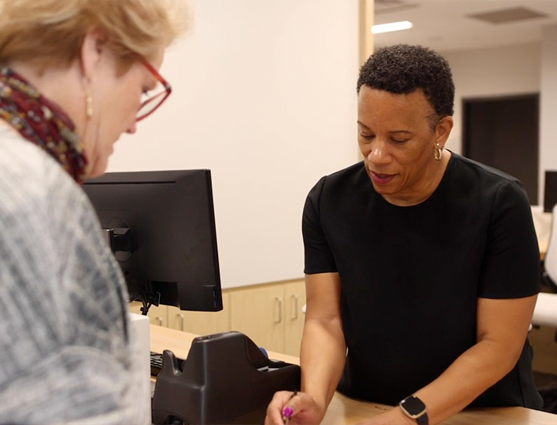 Woman talking to dental team member about the cost of dental implants