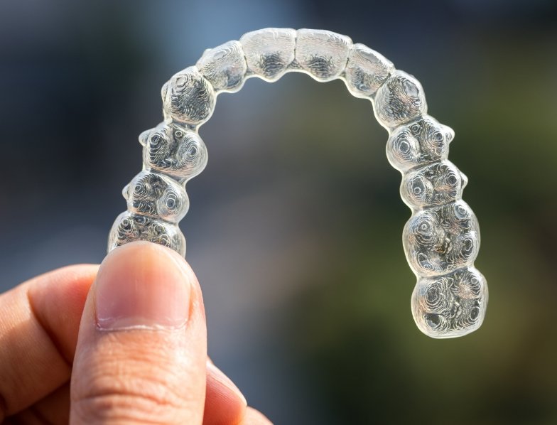 Hand holding an Invisalign clear aligner