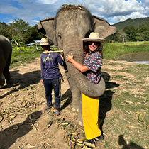 Doctor Velasco posing with an elephant wrapping its trunk around her