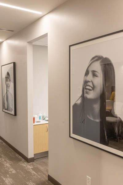 Photos of smiling people on dental office hallway