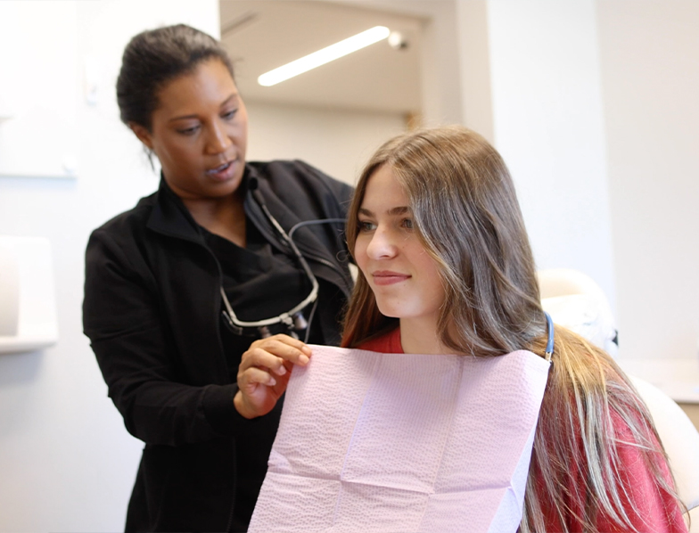 Dental team member placing a dental bib on a patient