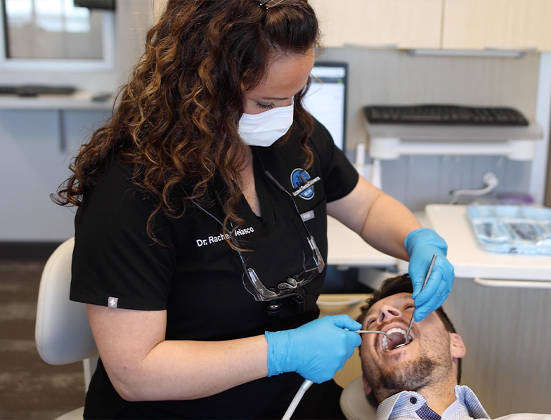 Dental team member examining a patient's mouth