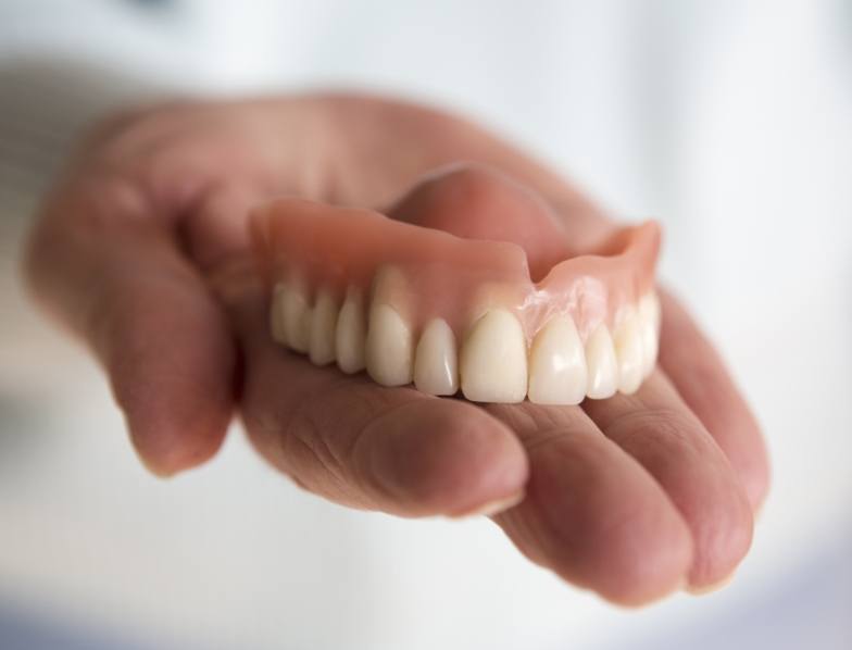 Person holding a full denture in their hand