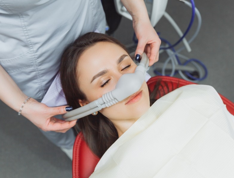 Woman laying back in dental chair and wearing nitrous oxide sedation mask