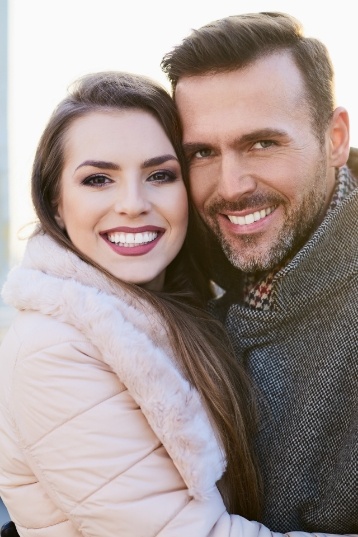 Man and woman grinning and holding each other