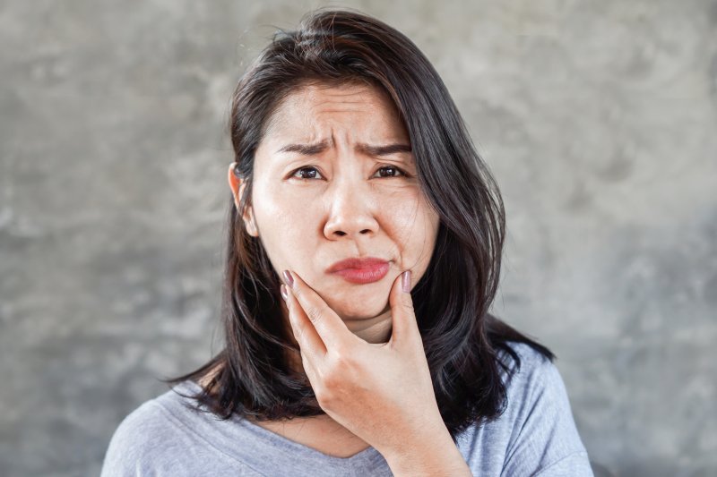 A woman rubbing her jaw due to facial swelling